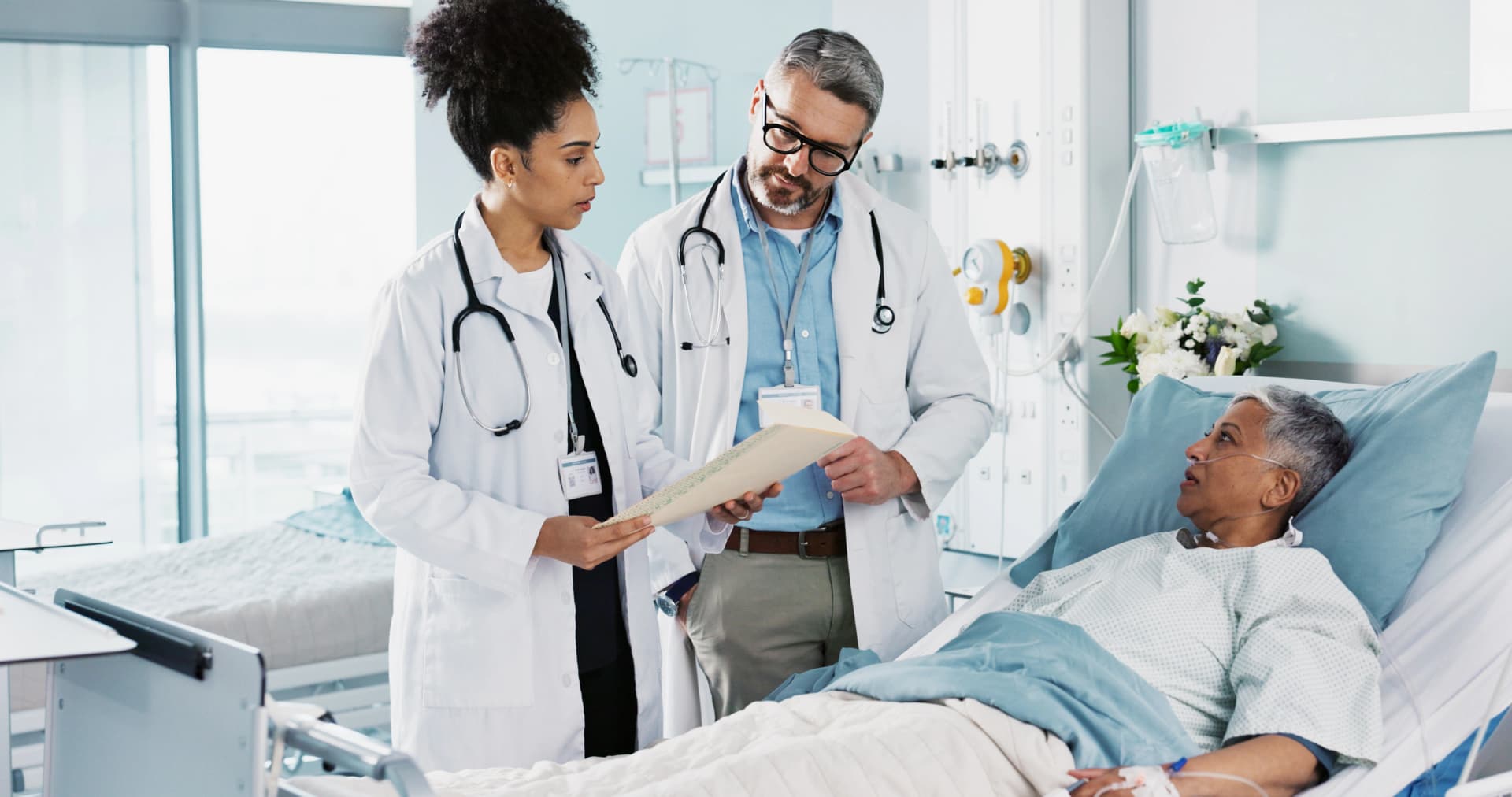 Two doctors reviewing a patient's chart together on a hospital ward
